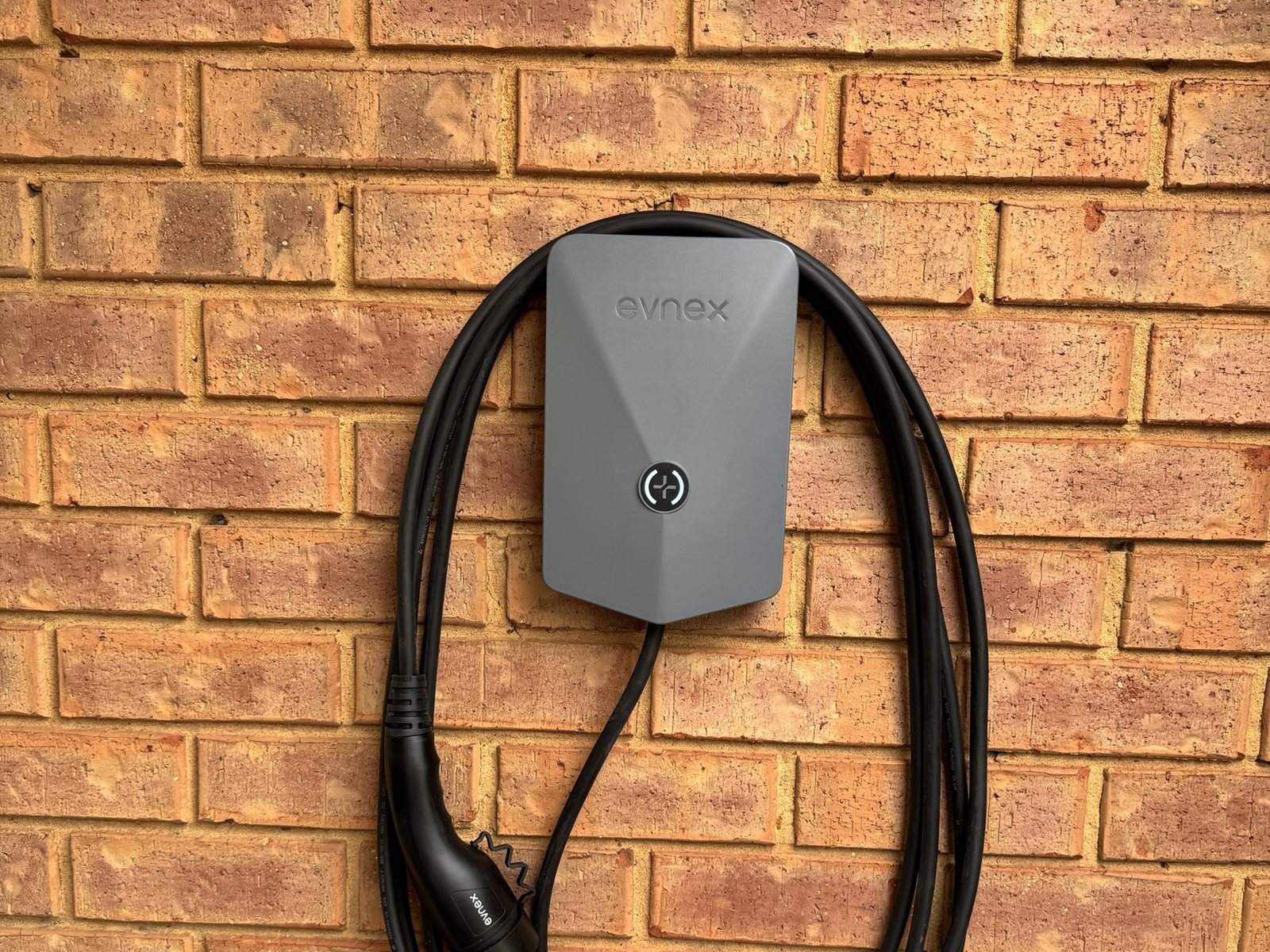 Grey Evnex Core charger on a brick wall with the cable coiled