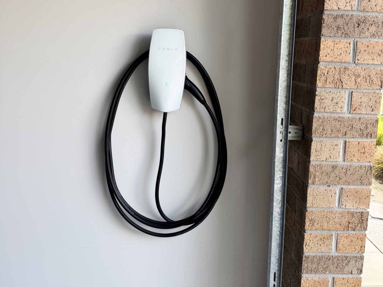 White Tesla Wall Connector on a garage wall with the cable coiled